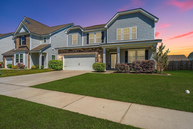 view of front of property with a front lawn, fence, stone siding, concrete driveway, and an attached garage