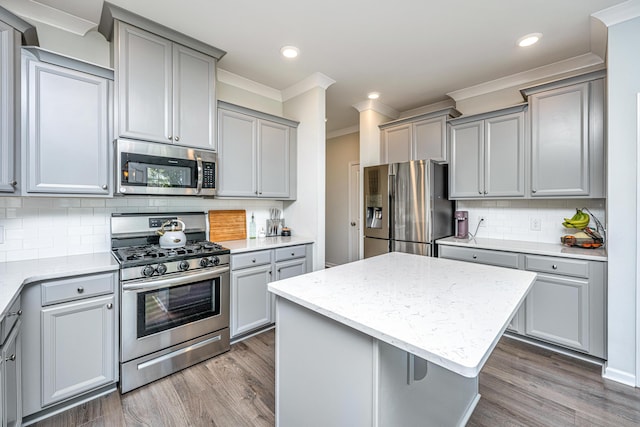 kitchen with ornamental molding, dark wood-style floors, tasteful backsplash, appliances with stainless steel finishes, and gray cabinetry