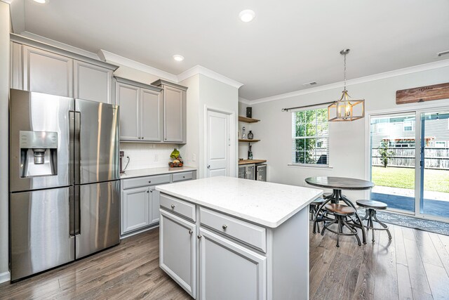kitchen with stainless steel fridge, gray cabinets, wood finished floors, and crown molding