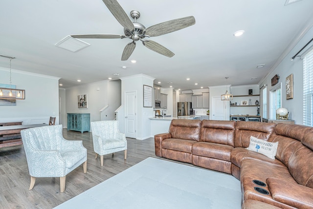 living room featuring light wood finished floors, a ceiling fan, recessed lighting, visible vents, and ornamental molding