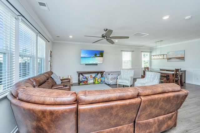 living area featuring ceiling fan, ornamental molding, wood finished floors, and visible vents