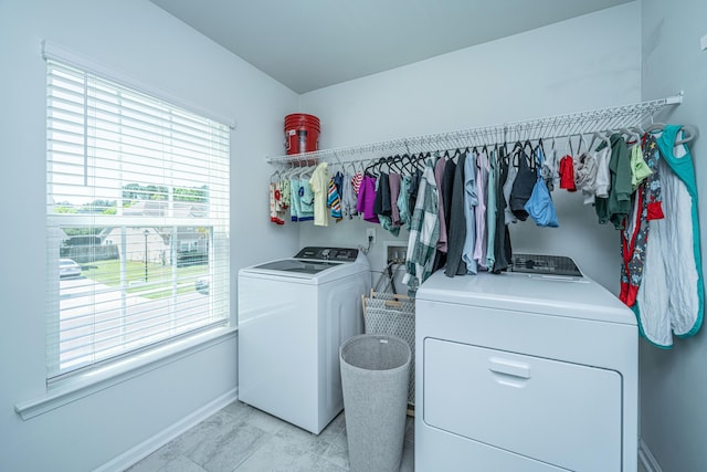 washroom featuring baseboards, laundry area, washing machine and dryer, and a wealth of natural light