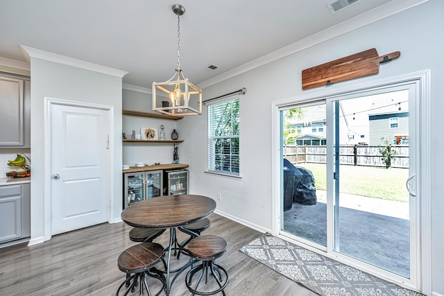 dining space with visible vents, wood finished floors, beverage cooler, an inviting chandelier, and ornamental molding