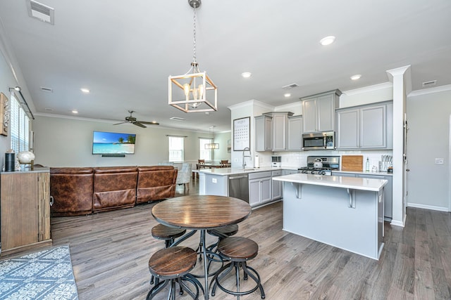 kitchen featuring visible vents, appliances with stainless steel finishes, gray cabinetry, light countertops, and ornamental molding