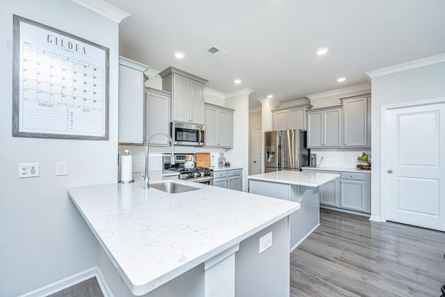 kitchen with a kitchen breakfast bar, visible vents, appliances with stainless steel finishes, gray cabinetry, and a sink