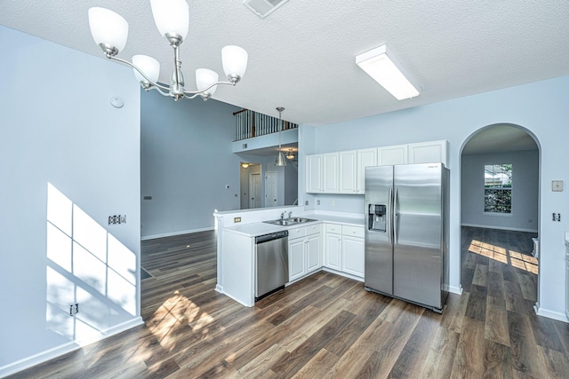 kitchen featuring sink, hanging light fixtures, stainless steel appliances, white cabinets, and kitchen peninsula