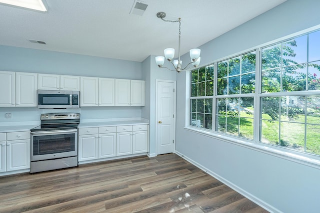 kitchen with hanging light fixtures, dark hardwood / wood-style floors, white cabinets, and appliances with stainless steel finishes