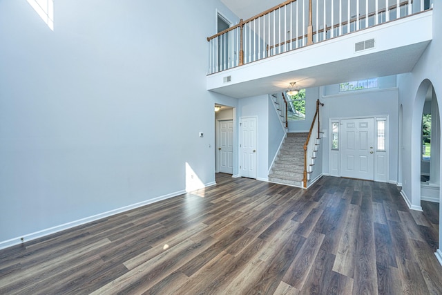 entryway with a towering ceiling and dark hardwood / wood-style flooring