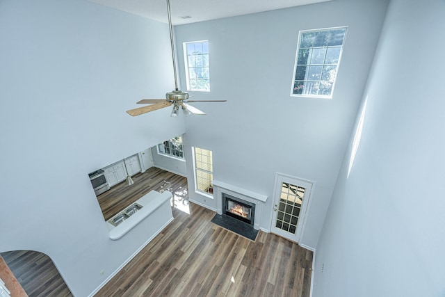 living room featuring ceiling fan, dark hardwood / wood-style floors, and a towering ceiling