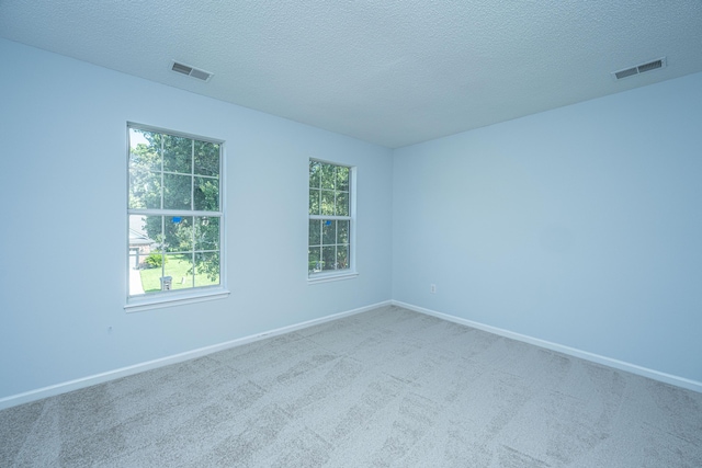 unfurnished room with a healthy amount of sunlight, carpet flooring, and a textured ceiling