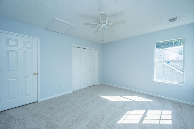 unfurnished bedroom featuring light carpet, ceiling fan, a closet, and a textured ceiling