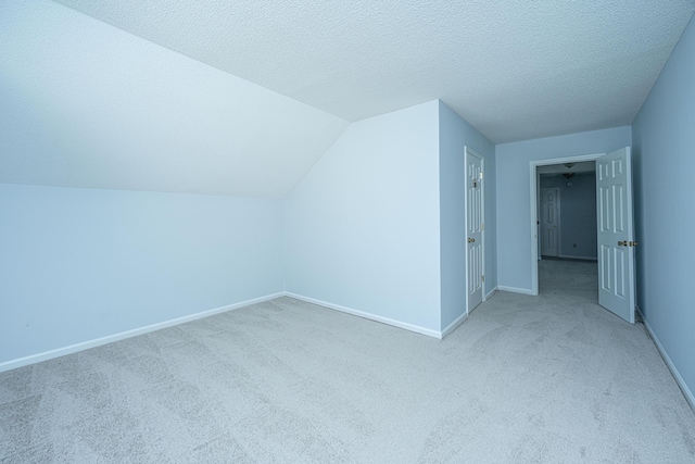 bonus room with vaulted ceiling, light colored carpet, and a textured ceiling