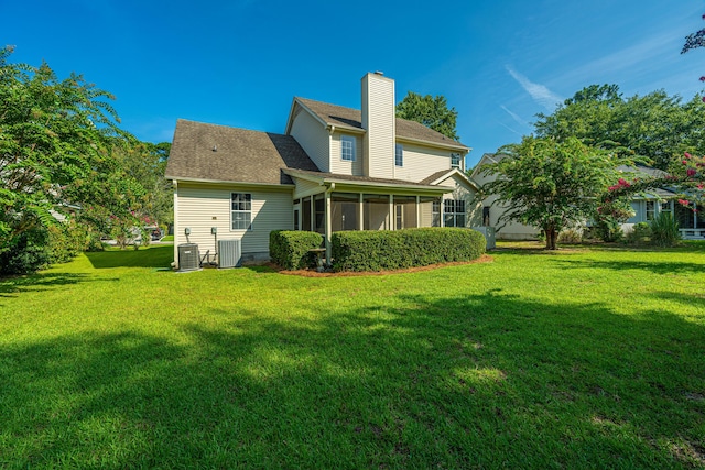 rear view of house featuring a sunroom, a yard, and cooling unit