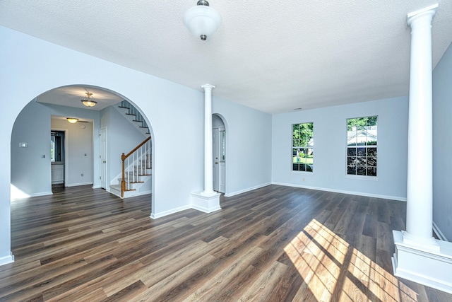 unfurnished living room featuring dark hardwood / wood-style flooring, decorative columns, and a textured ceiling