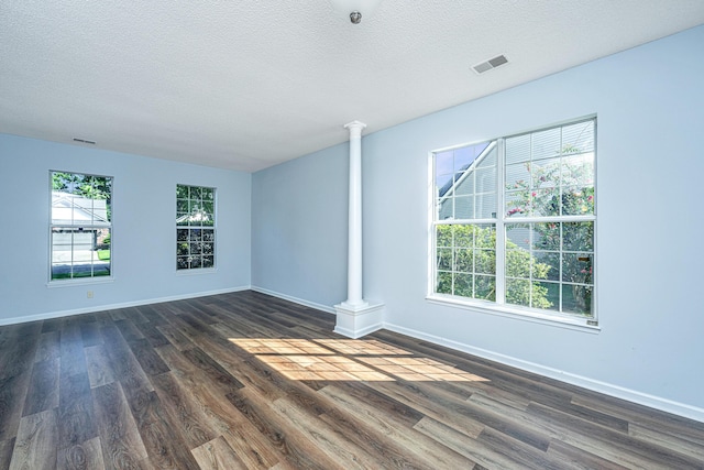 unfurnished room with dark hardwood / wood-style flooring, decorative columns, and a textured ceiling