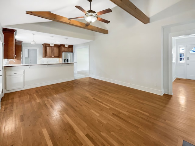 unfurnished living room with lofted ceiling with beams, light wood-type flooring, and ceiling fan