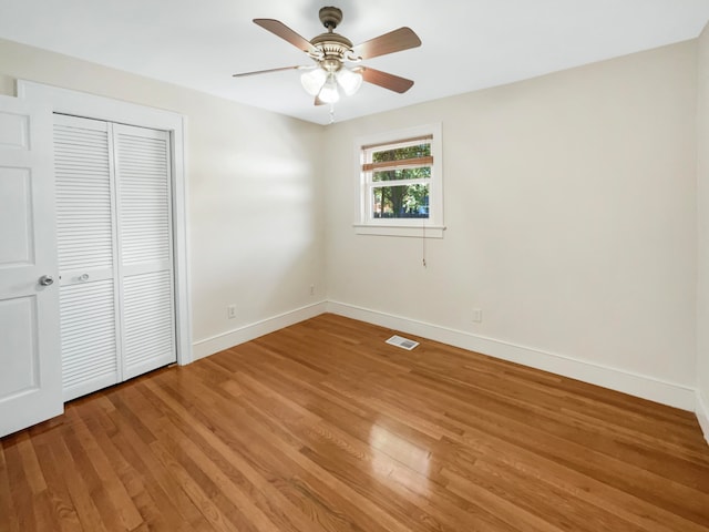 unfurnished bedroom featuring a closet, hardwood / wood-style floors, and ceiling fan