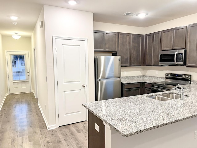 kitchen featuring appliances with stainless steel finishes, light stone counters, kitchen peninsula, and dark brown cabinetry