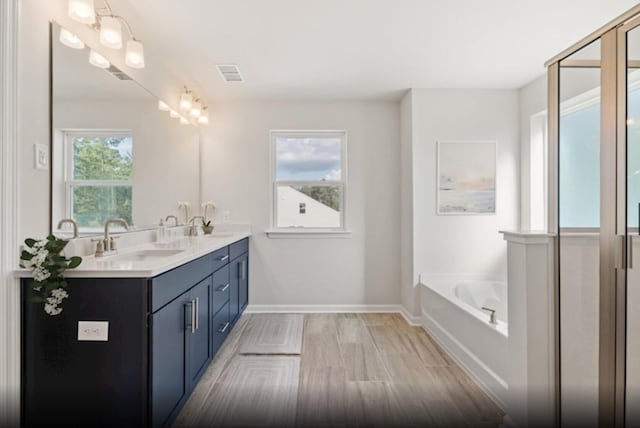 bathroom with wood-type flooring, a bath, and vanity