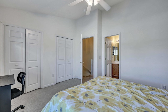 bedroom with two closets, ensuite bath, light colored carpet, and ceiling fan