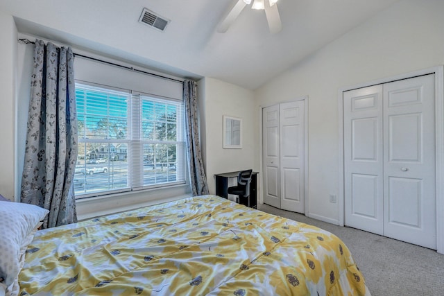 carpeted bedroom featuring ceiling fan, vaulted ceiling, and two closets