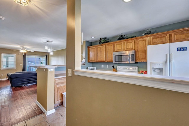 kitchen with pendant lighting, a kitchen bar, stove, white fridge with ice dispenser, and kitchen peninsula