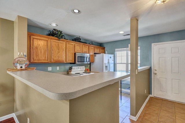 kitchen with white appliances, a kitchen breakfast bar, kitchen peninsula, and light tile patterned floors