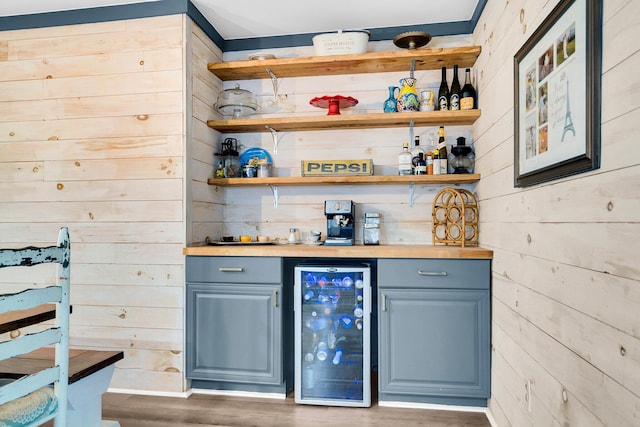 bar featuring wine cooler, dark hardwood / wood-style flooring, wooden walls, and gray cabinets