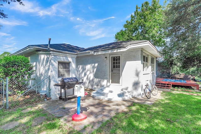 rear view of property featuring a wooden deck, a patio area, and a yard