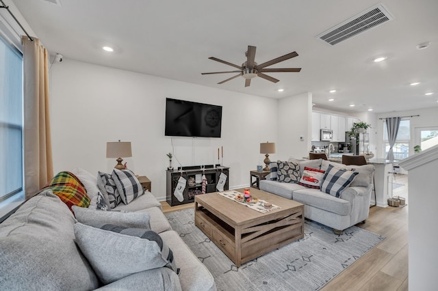 living room with light hardwood / wood-style floors and ceiling fan