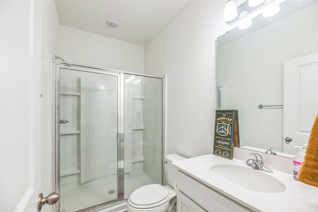 bathroom featuring vanity, a shower with shower door, and toilet