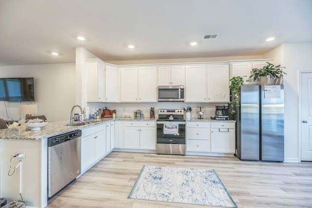 kitchen featuring sink, light hardwood / wood-style flooring, white cabinetry, kitchen peninsula, and stainless steel appliances