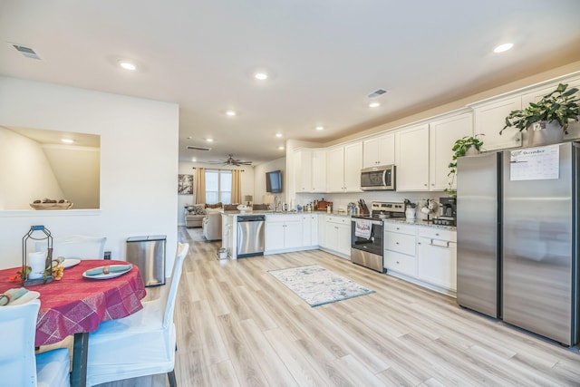 kitchen featuring ceiling fan, stainless steel appliances, light hardwood / wood-style flooring, kitchen peninsula, and white cabinets