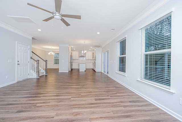 unfurnished living room featuring crown molding, ceiling fan with notable chandelier, and light wood-type flooring