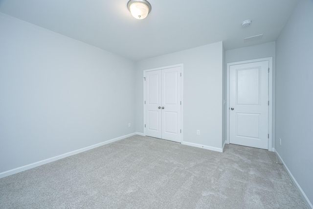 unfurnished bedroom featuring light colored carpet and a closet