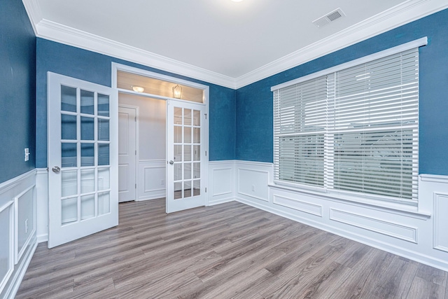 empty room featuring hardwood / wood-style floors, ornamental molding, and french doors