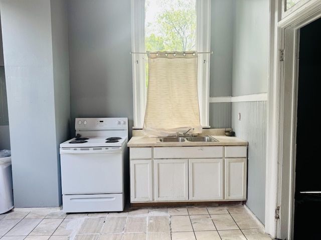 kitchen with light countertops, white electric stove, white cabinetry, and a sink