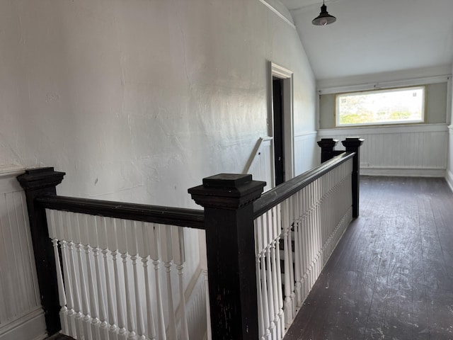 interior space featuring wainscoting, vaulted ceiling, an upstairs landing, a decorative wall, and hardwood / wood-style flooring