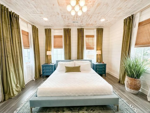 bedroom featuring dark hardwood / wood-style flooring, wood ceiling, an inviting chandelier, and multiple windows