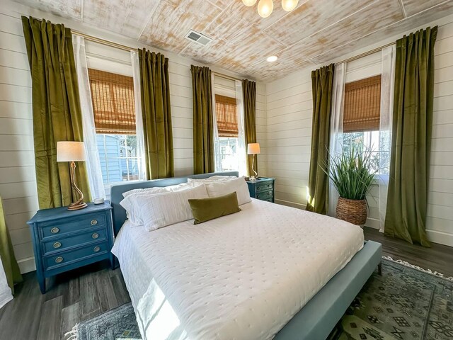 bedroom with dark hardwood / wood-style floors, wood ceiling, and wooden walls