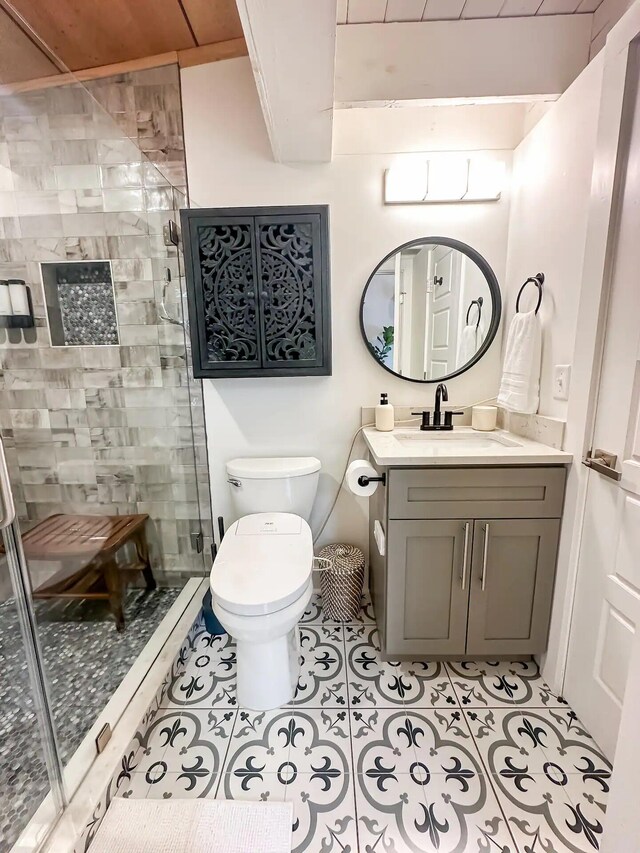 bathroom featuring tile patterned flooring, toilet, a shower with door, and vanity