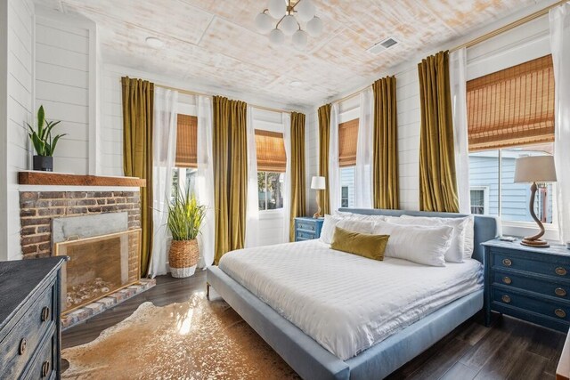 bedroom featuring a fireplace, dark hardwood / wood-style floors, and wood ceiling