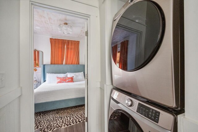 laundry room with hardwood / wood-style flooring and stacked washer and clothes dryer