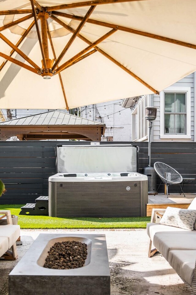 view of patio / terrace with an outdoor fire pit and a hot tub