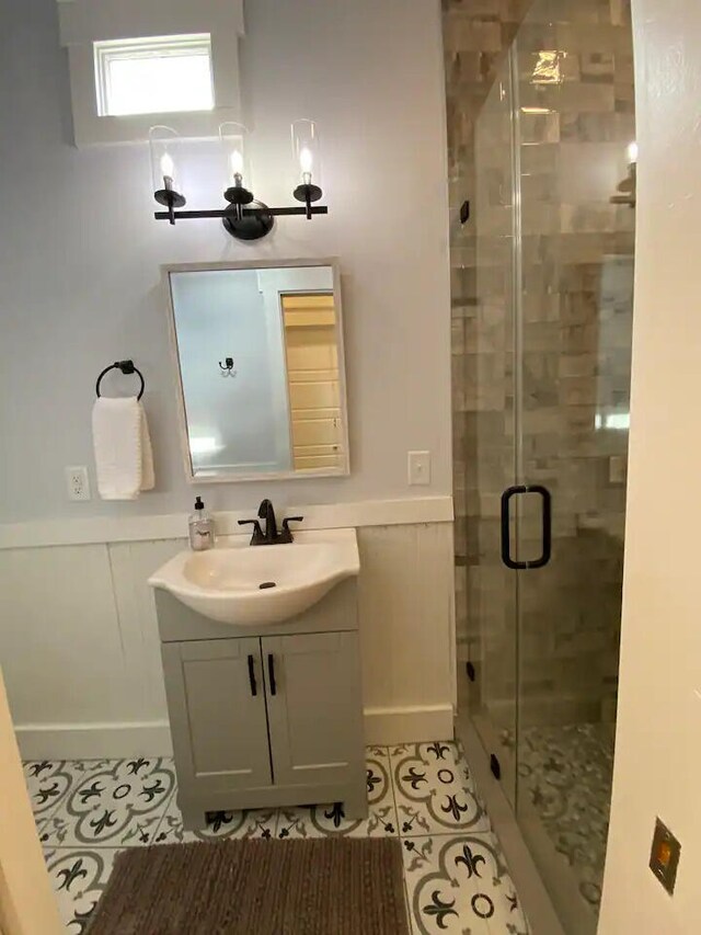 bathroom featuring tile patterned flooring, a shower with shower door, and vanity