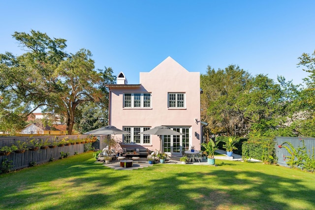 rear view of property featuring a lawn, a jacuzzi, and a patio