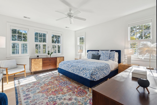 bedroom with ceiling fan, wood-type flooring, and multiple windows