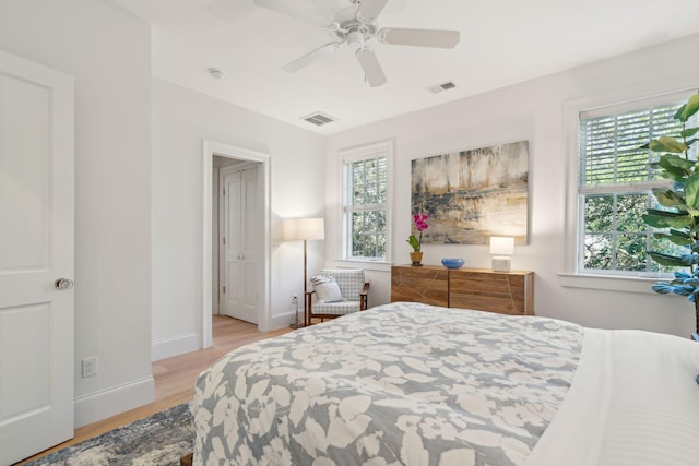 bedroom with multiple windows, light hardwood / wood-style floors, and ceiling fan