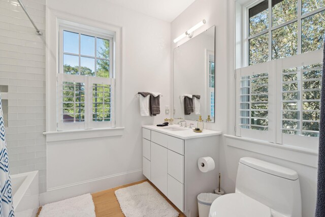 full bathroom with a wealth of natural light, shower / bath combo with shower curtain, vanity, and hardwood / wood-style flooring