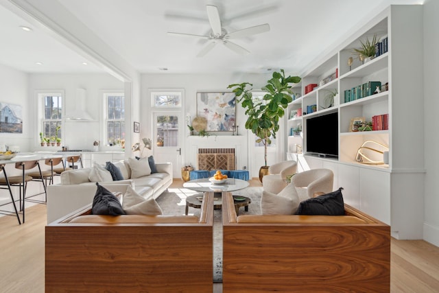 living room featuring ceiling fan, light hardwood / wood-style floors, and a fireplace